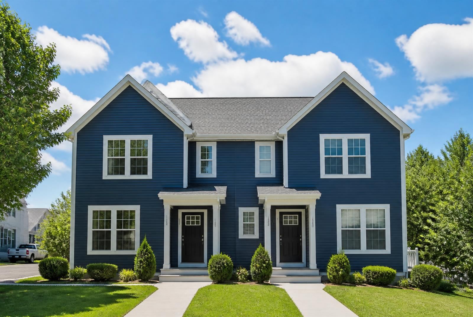 Navy blue two-story townhome duplex with white trim on a sunny day